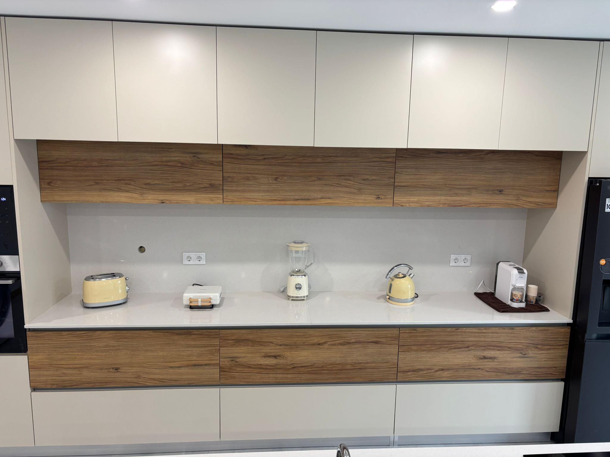 Cozinha branca com painel de madeira e eletrodomésticos pequenos